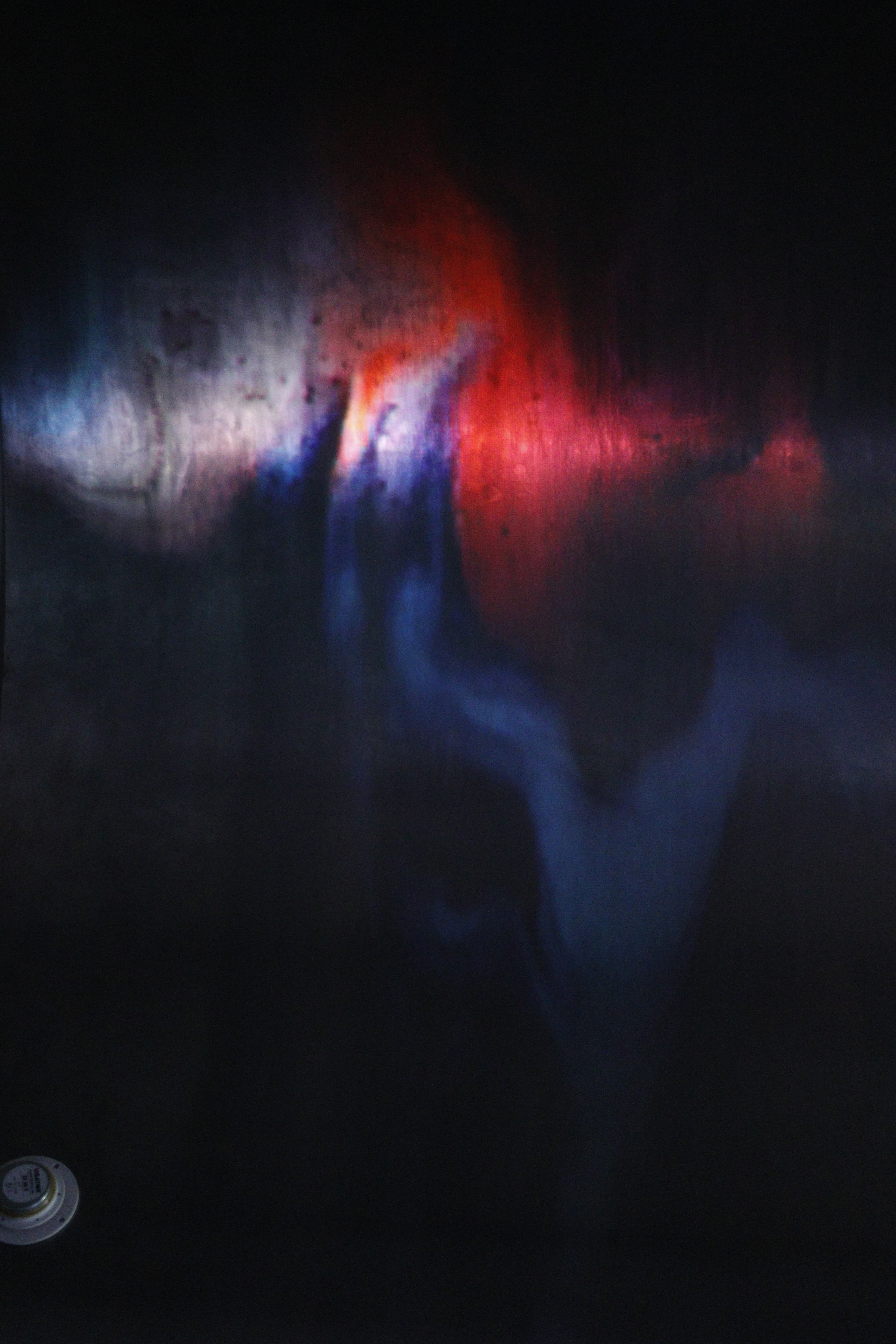 The image is dark with red and purple abstract shapes moving across it. 